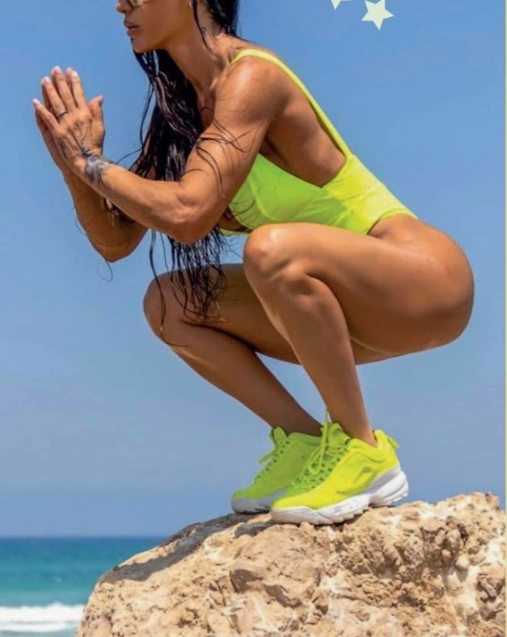 אמה גלים בסקוואט על סלע מול הים